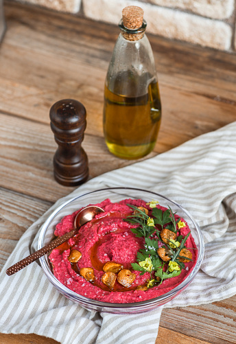beetroot hummus dip in rustic kitchen with olive oil, roasted garlic and parsley