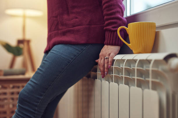 Woman heating on a chilly winter day, energy and gas crisis, cold room, heating problems. stock photo