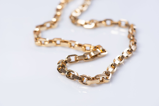 Women`s gold necklace on white background. Top view