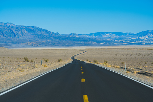 Cars driving on a remote Interstate road in the desert of Death Valley, California.