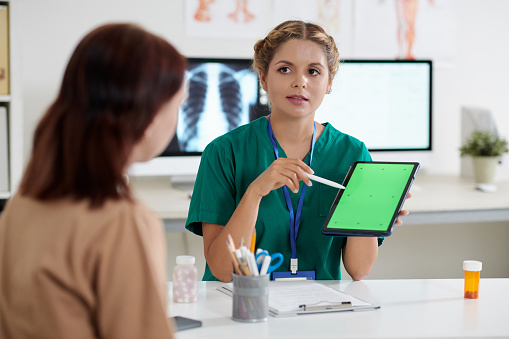 Pulmonologist pointing at tablet computer when green screen when talking to patient