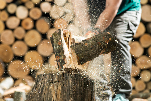 Hand and axe in firewood, chopping wood for fire heat