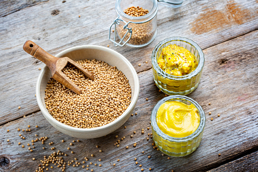 Different types of mustard and mustard seeds on a rustic wooden board - copy space