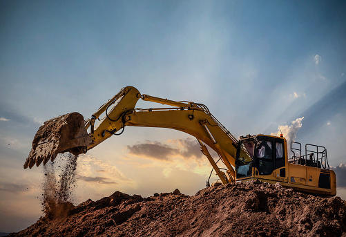 Excavator at a construction site against sunset sky