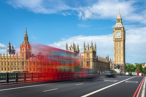 Red double decker bus with motion blur on Westminster bridge, Big Ben in the background, in London, UK