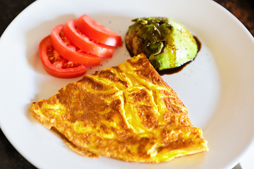Low-carbohydrate meal of cheese omelette, tomato and avocado.