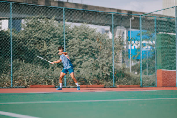 giovane tennista asiatico professionista cinese che gioca a tennis in campo duro - tennis asian ethnicity male forehand foto e immagini stock