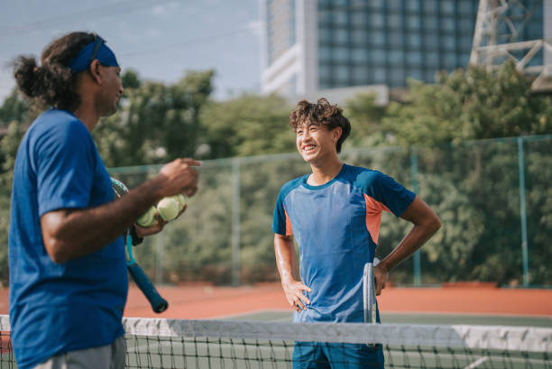 아시아계 중국인 젊은 남자 테니스 선수가 아침에 일상적인 훈련을 연습하는 동안 코치를 듣는 것 - tennis court sports training tennis net 뉴스 사진 이미지