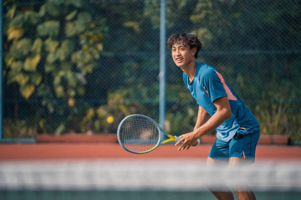 wesoły chiński młody tenisista uśmiechający się na twardym korcie ćwiczącym - tennis men vitality joy zdjęcia i obrazy z banku zdjęć