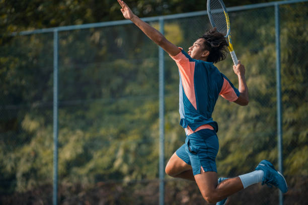un joueur de tennis chinois d’origine asiatique sautant dans les airs servant sur un court dur - tennis asian ethnicity male forehand photos et images de collection