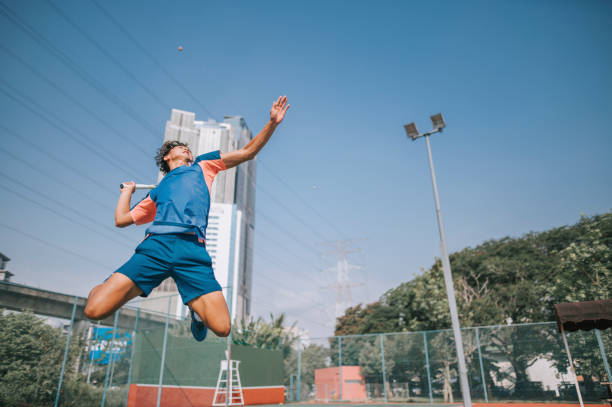 joueur de tennis asiatique chinois sautant dans les airs en servant sur un terrain en dur - tennis asian ethnicity male forehand photos et images de collection