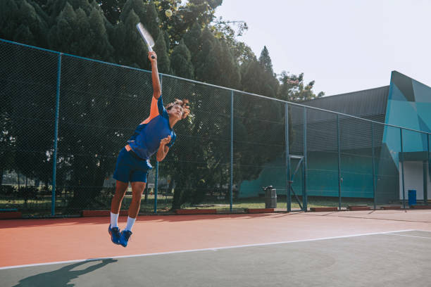 habile joueur de tennis chinois d’origine asiatique sautant dans les airs servant sur un court dur - tennis asian ethnicity male forehand photos et images de collection