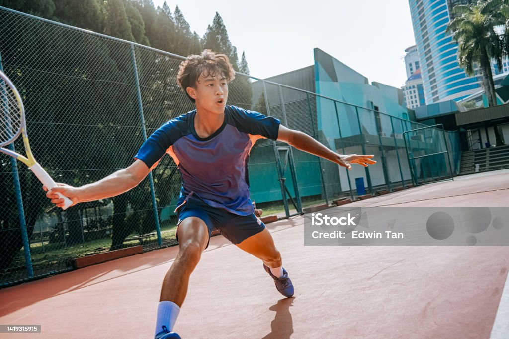 aggressive asian Chinese male tennis player aiming to hit tennis ball in hardcourt tennis competition Athlete Stock Photo