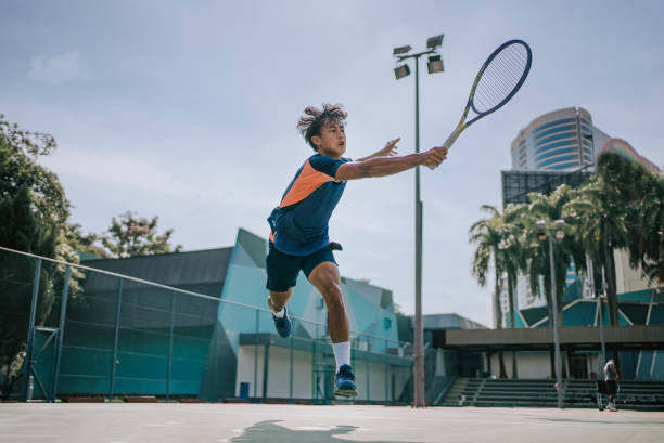 habile joueur de tennis asiatique chinois sautant dans les airs pour faire un sauvetage - tennis asian ethnicity male forehand photos et images de collection