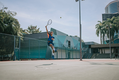 skilful Asian Chinese tennis player jumping mid air making a save