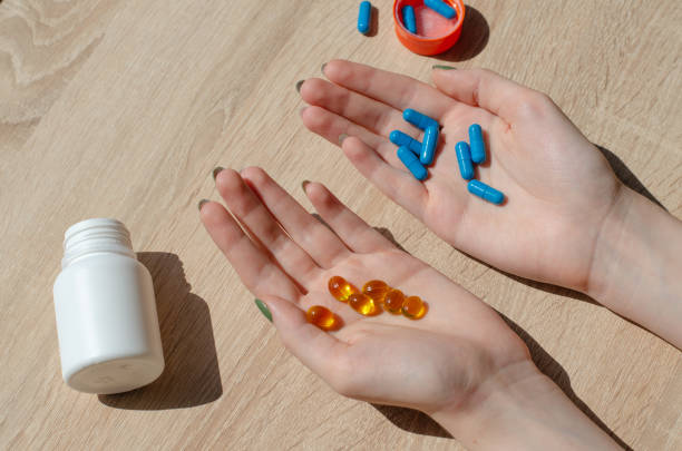 istock Plastic jar for pills. White jar with orange lid. Cold medicine. Pharmaceutical activity. The patient takes the pills. The girl holds multi-colored capsules with cure for the disease. Vitamins. 1419318399