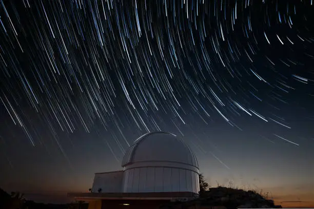 Photo of Astronomical observatory under star trails sky at night