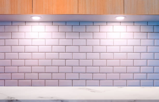 Empty white marble counter with lighting on white tile wall and wooden cabinet in modern kitchen room
