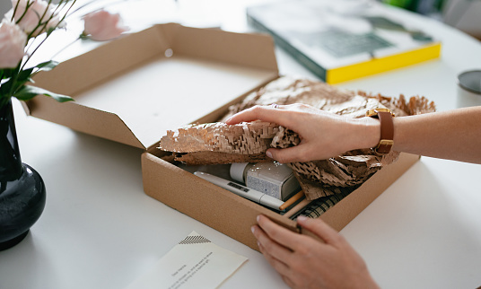 Close up shot of anonymous woman's hands removing the wrapping paper to reveal the content of a gift box she received.