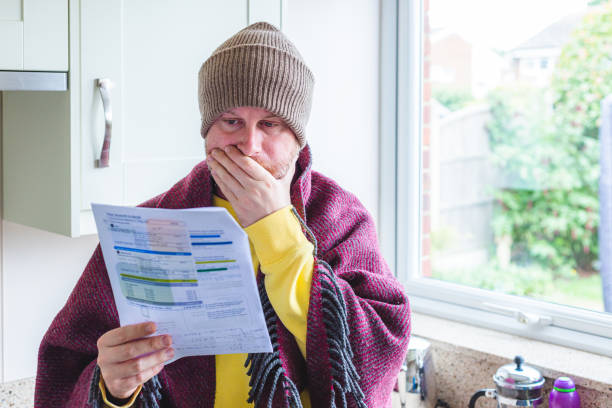 Cold and worried man checking bills at home