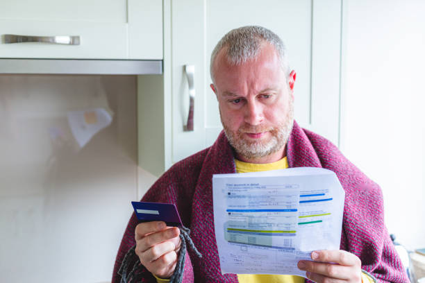 Cold and worried man checking bills at home