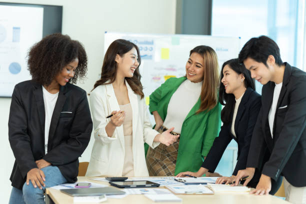istock Business people showing team work while working in board room in office interior. People helping one of their colleague to finish new business plan. Business concept. Team work. 1419338206