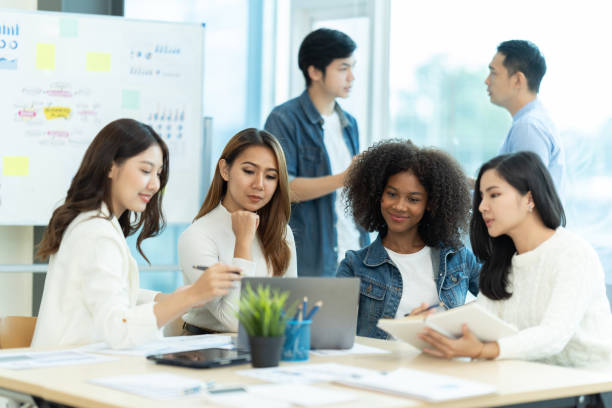 istock Business people showing team work while working in board room in office interior. People helping one of their colleague to finish new business plan. Business concept. Team work. 1419338399