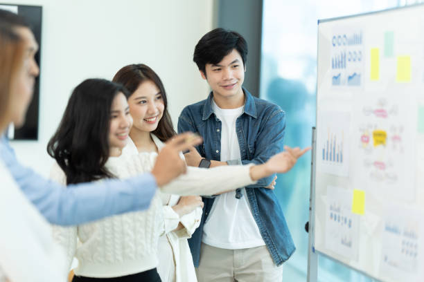 istock Business people showing team work while working in board room in office interior. People helping one of their colleague to finish new business plan. Business concept. Team work. 1419339655