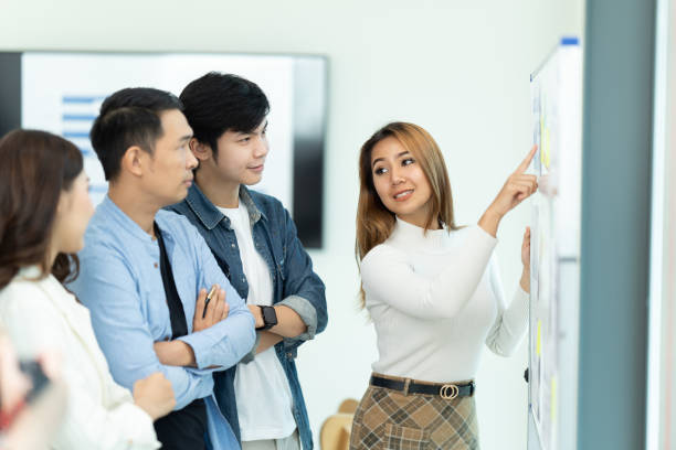 istock Business people showing team work while working in board room in office interior. People helping one of their colleague to finish new business plan. Business concept. Team work. 1419340236