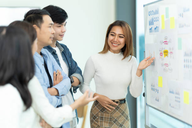 istock Business people showing team work while working in board room in office interior. People helping one of their colleague to finish new business plan. Business concept. Team work. 1419341391