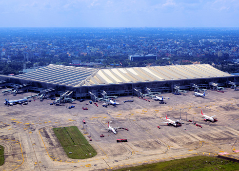 Kolkata / Calcutta, West Bengal, India: Netaji Subhash Chandra Bose International Airport / Dum Dum Airport (IATA: CCU, ICAO: VECC), seen from the air - main terminal ( integrated terminal T2) and apron with Air India and IndiGo aircraft. The airport is a major hub for Northeast India, Bangladesh, Bhutan, China and Southeast Asia.