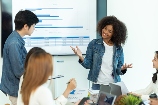 Business people showing team work while working in board room in office interior. People helping one of their colleague to finish new business plan. Business concept. Team work.