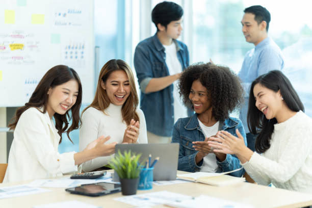 geschäftsleute, die teamarbeit zeigen, während sie im sitzungssaal im büroinneren arbeiten. menschen, die einem ihrer kollegen helfen, einen neuen geschäftsplan zu erstellen. geschäftskonzept. teamarbeit. - thai culture fotos stock-fotos und bilder