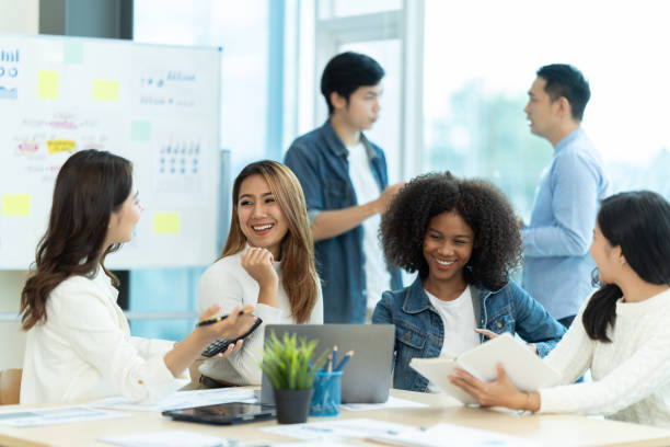 istock Business people showing team work while working in board room in office interior. People helping one of their colleague to finish new business plan. Business concept. Team work. 1419345593