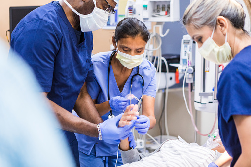A multiracial emergency room team works on an unrecognizable young adult female patient.