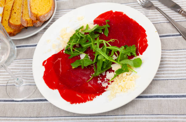 Plate of healthy fresh salad with arugula, beetroot, and white cheese served on rustic wooden background.