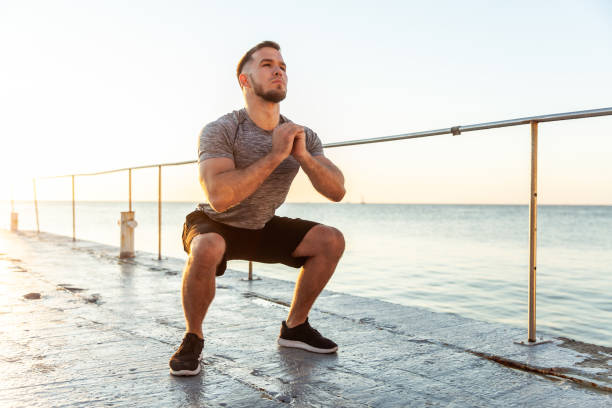 istock Athletic man practicing squats in the early morning on the beach 1419356266