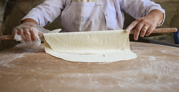 A woman rolling out the dough with a rolling pin