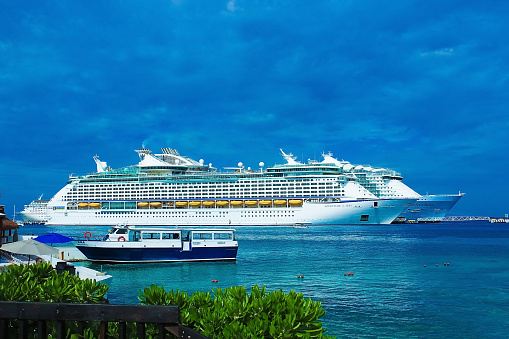 Miami, Florida - April 29, 2023: Three crewmembers of a cruise ship walk over the Port Blvd bridge toward their ship in the port of Miami. On the left is Terminal V, home to Virgin Voyages.