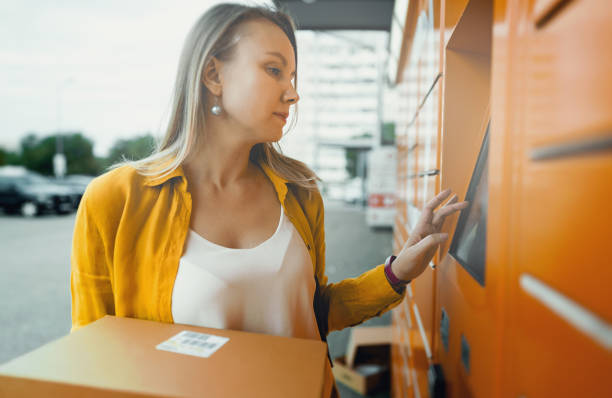 istock Woman sending mail via automated self-service post terminal machine. 1419363159