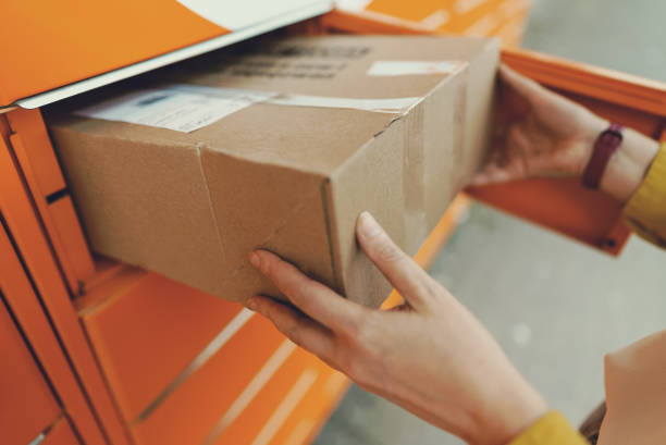 istock Woman sending mail via automated self-service post terminal machine. 1419363160