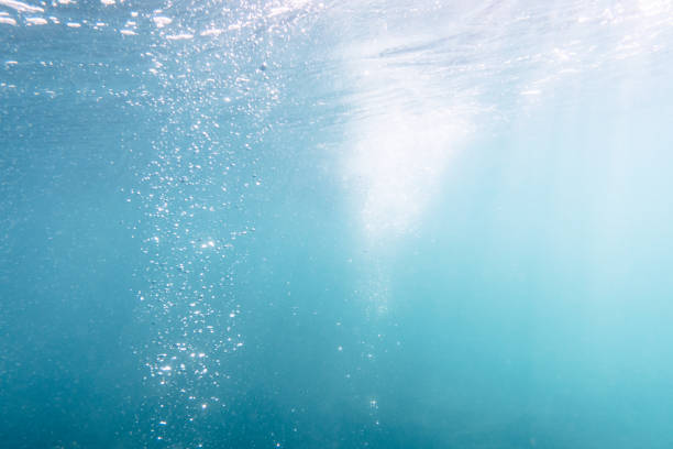 A scuba diver's exhaled air travels to the surface of the sea.  Air Bubble Blue sea Underwater sunlight background   Scuba diver point of view
