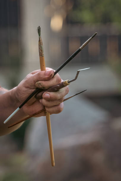 istock Artist's hand with brushes, spatula and other tools 1419364233