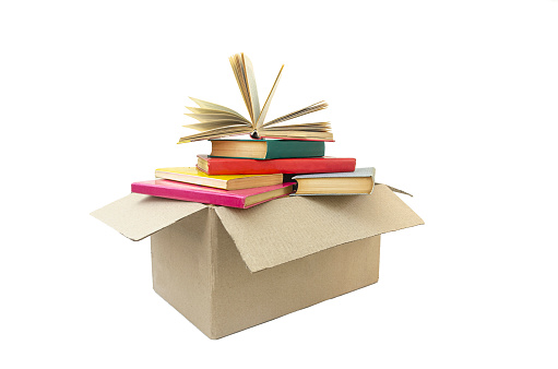 Moving house cardboard box filled with books, isolated on white background.