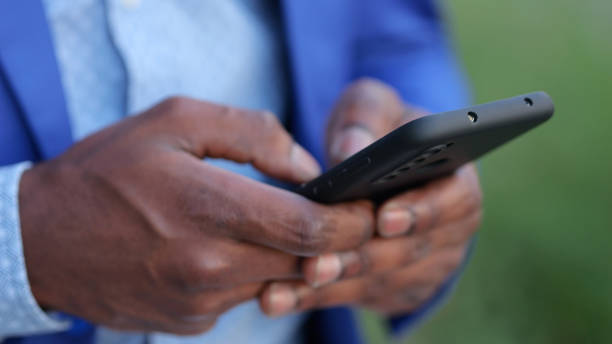 istock Black man in blue blazer enters information into phone 1419366379