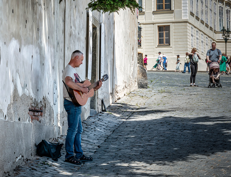 Prague, Czech Republic - June 2022: Adult street artist in the old town of Prague playing acoustic guitar for tourists.