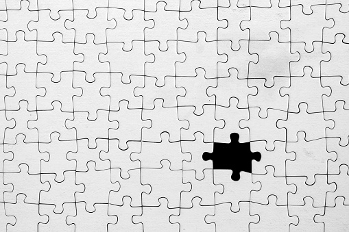Purple background showing through missing piece in white jigsaw puzzle.