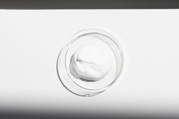 istock Texture of a white cosmetic product in a container close-up with bright sunlight, top view. Face cream, lotion, body care shampoo. 1419367148