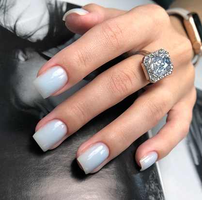 White manicure. Hands of a woman with white manicure on nails.Manicure beauty salon concept. Empty place for text or logo.