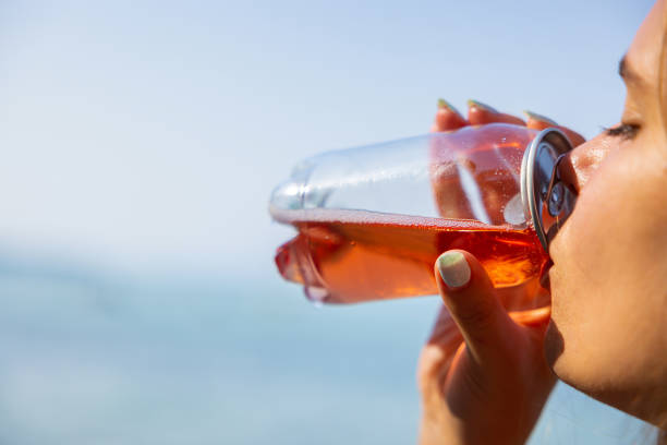 Unrecognizable young Caucasian woman drinking ice tea from the transparent plastic can